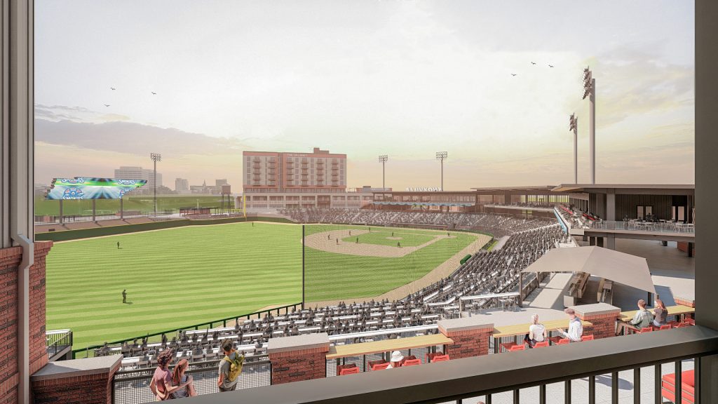 Apartments For Rent Downtown Knoxville View of a baseball stadium with a field, seating, and a scoreboard. People are sitting in the stands, and buildings are visible in the background under a cloudy sky. Knoxville Apartments