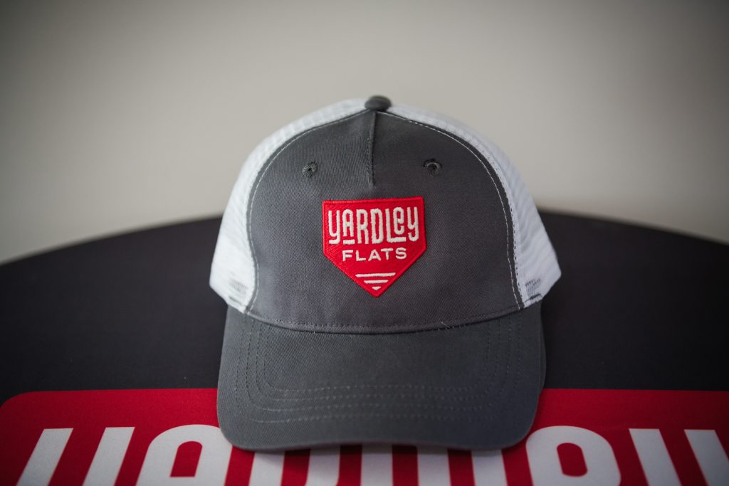 Apartments For Rent Downtown Knoxville Gray and white baseball cap with a red and white "Yardley Flats" logo on the front, placed on a surface with part of a red and white sign visible underneath. Knoxville Apartments