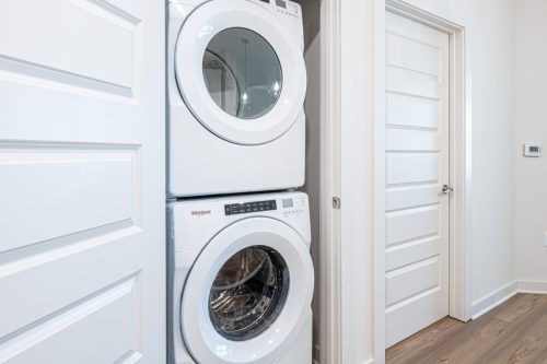 Apartments For Rent Downtown Knoxville A stacked white washer and dryer are positioned in a small laundry closet next to white paneled doors and a wood floor. Knoxville Apartments